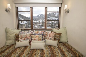 A room with a bed, patterned bedding, and a window with a view of a snowy town and mountains. - Charlie's Slopeside: Ski-In/Out Penthouse, Sleeps 12, 3,040 Sq Ft, AC, BC Village, Walk Everywhere (Beaver Creek)