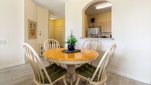 A dining room with a round wooden table, four chairs, and a potted plant.