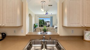 A kitchen with double sinks, a ceiling fan, and a view of a dining area with a table and chairs.