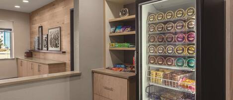 Habitación de hotel con pared de madera, minibar y nevera llena de alimentos congelados.