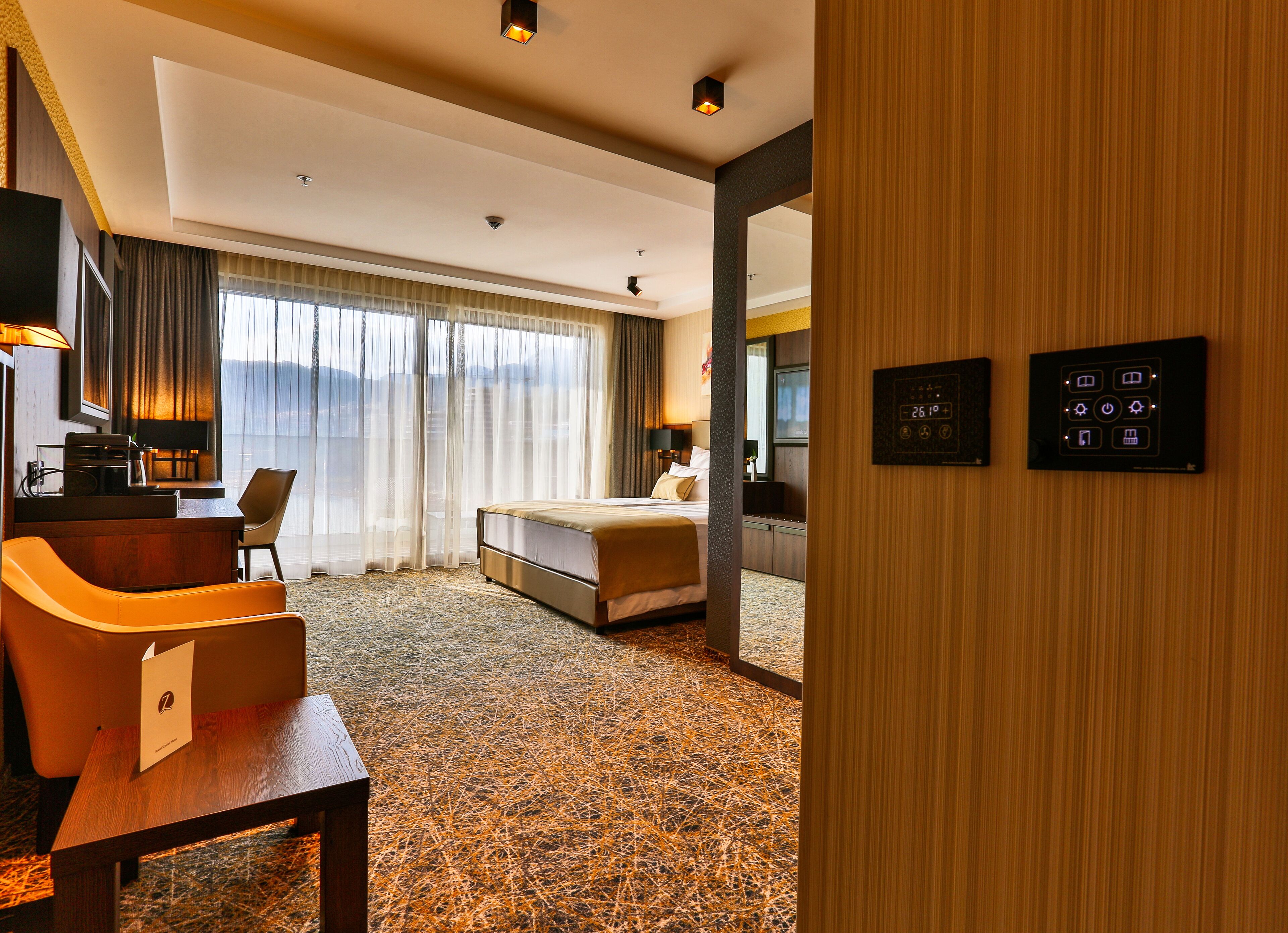 Una habitación de hotel con cama, escritorio, silla, televisor y vistas al exterior.