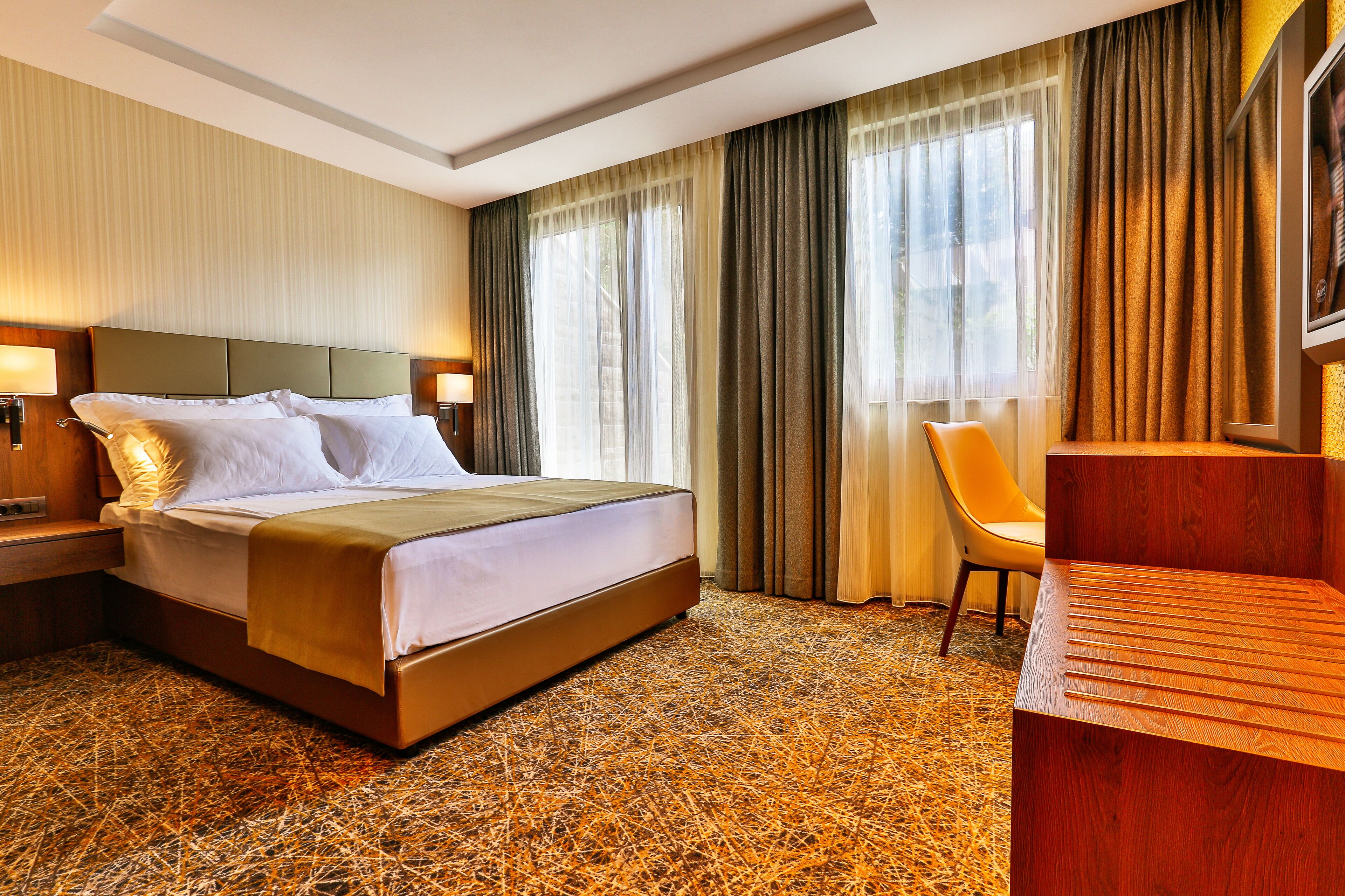 Habitación de hotel con una cama grande, un escritorio de madera y una silla.
