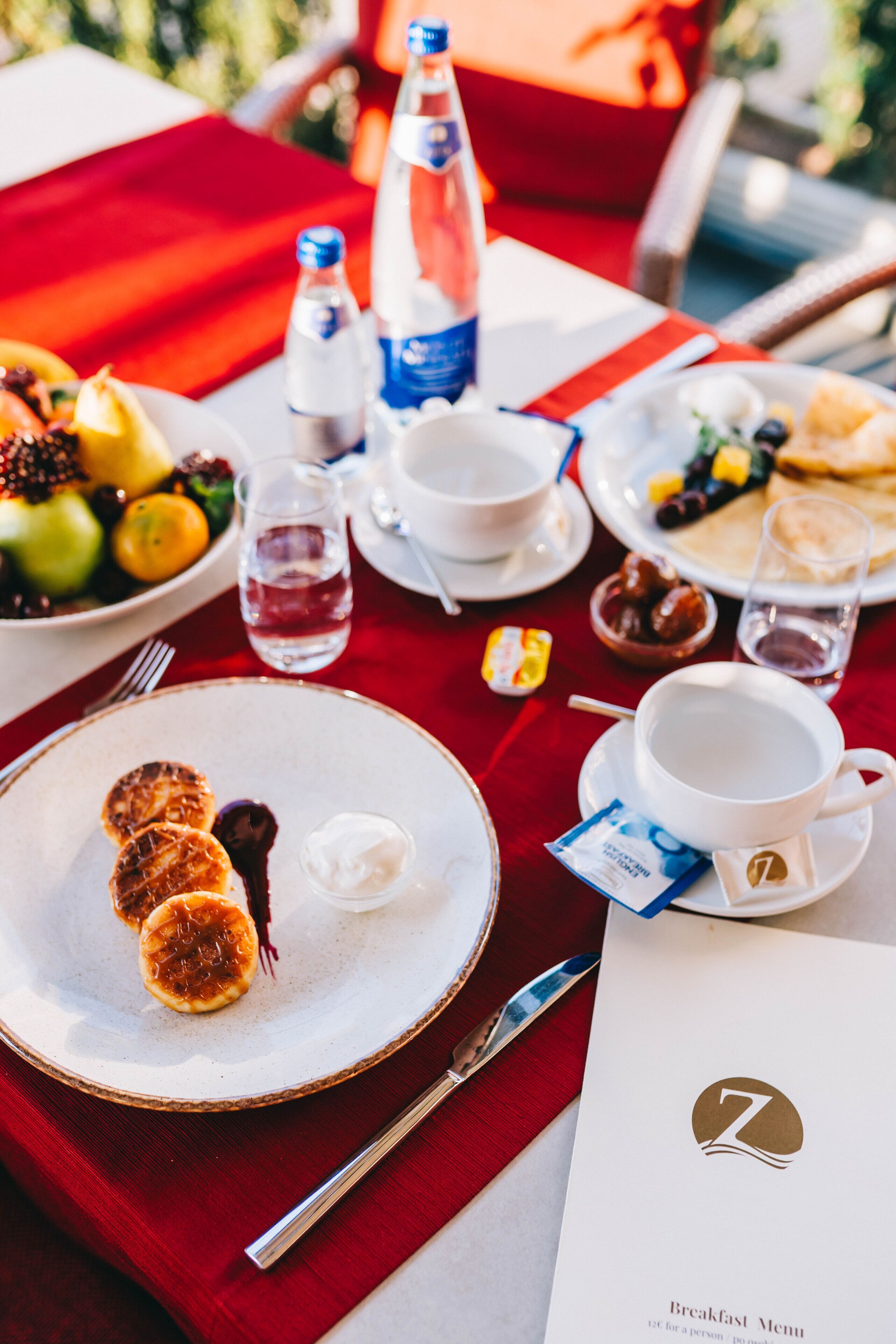 A breakfast setting with plates of food, a menu, and a bottle of water.