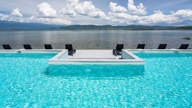 Piscina com vista para montanhas e um lago.