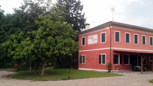 Ein rotes Gebäude mit einem Schild, auf dem "BARONE ROSSO" steht, und einem überdachten Außenbereich zum Sitzen.