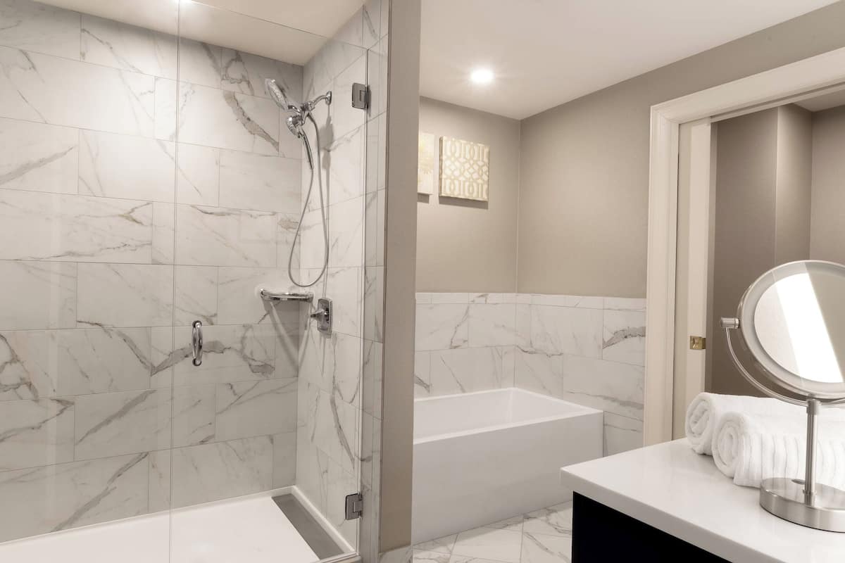 A modern bathroom with a glass-enclosed shower, a standalone bathtub, and a vanity with a mirror.