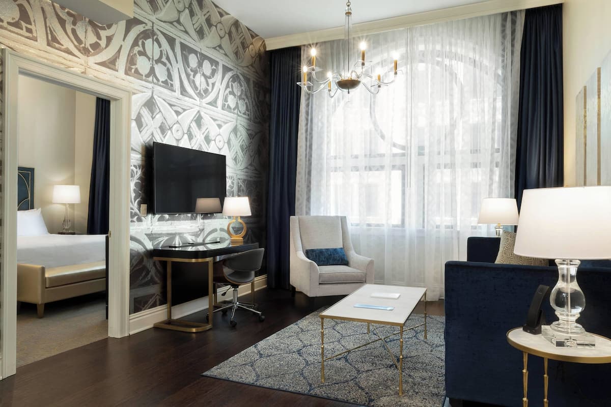 A hotel room with a bed, desk, chair, and a TV.