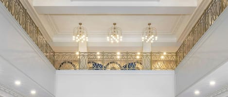 En storslagen entréhall med högt tak, utsmyckade kristallkronor och en central sittgrupp med blå klädda stolar.
