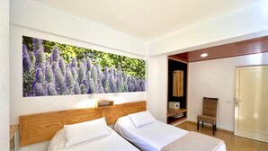 Habitación de hotel con dos camas, una obra de arte floral grande en la pared, un armario y una puerta.