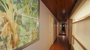 Un pasillo con piso de madera, un gran mural con motivos tropicales a la izquierda y una pared texturizada a la derecha.