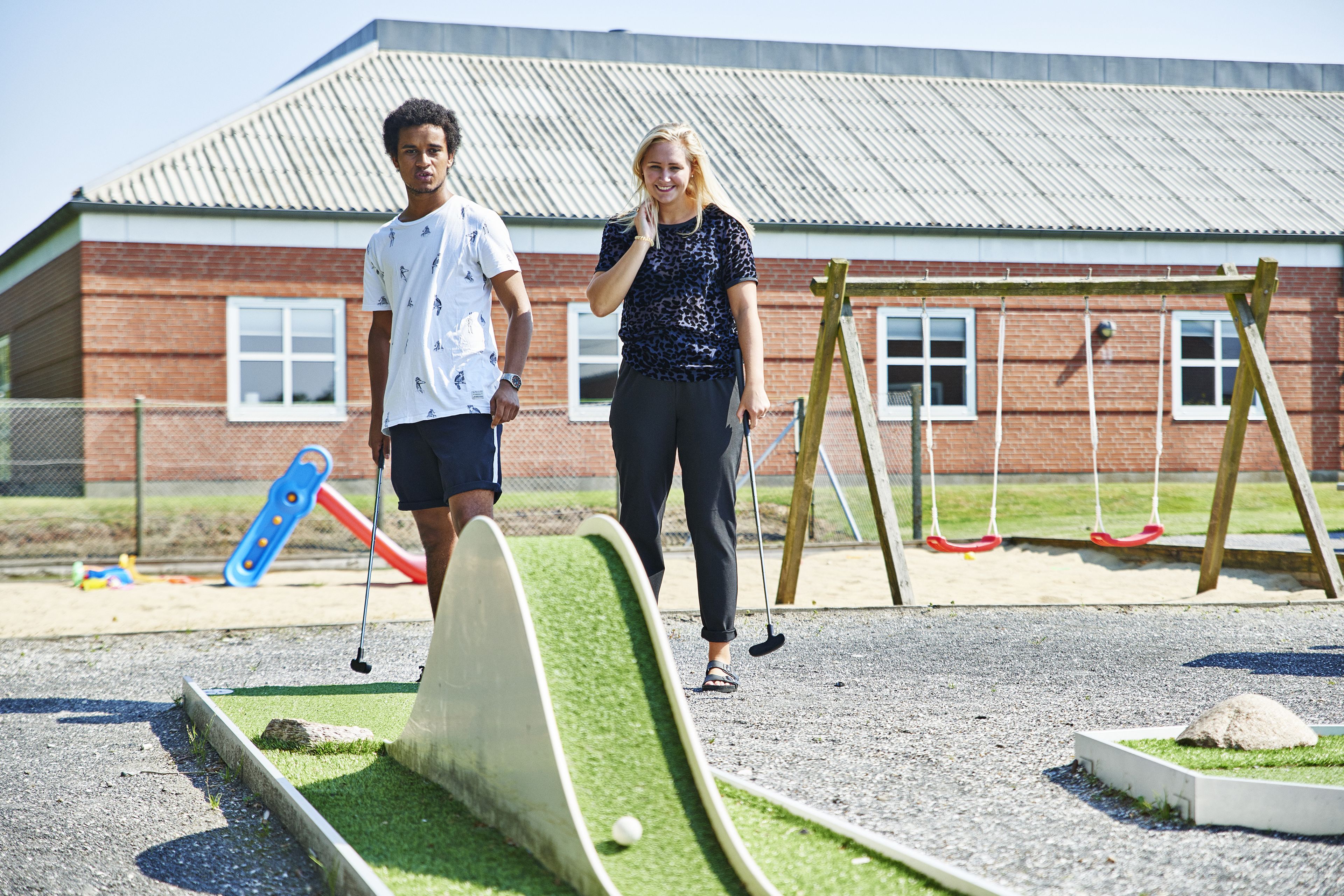 Un parcours de minigolf avec un bâtiment en briques en arrière-plan.