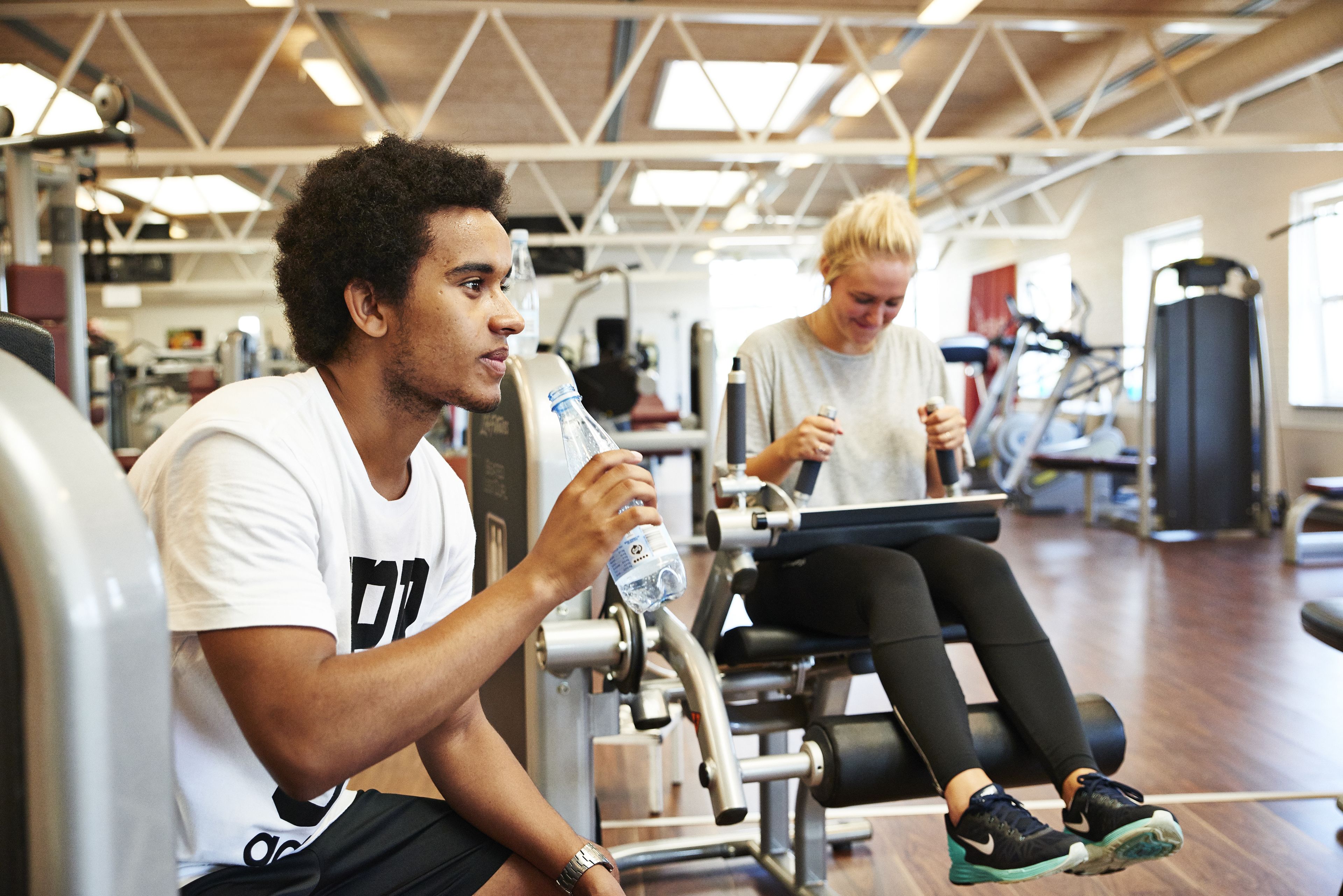 Un gimnasio con equipo de ejercicio y una persona sentada en una máquina.