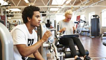 Un gimnasio con equipo de ejercicio y una persona sentada en una máquina.