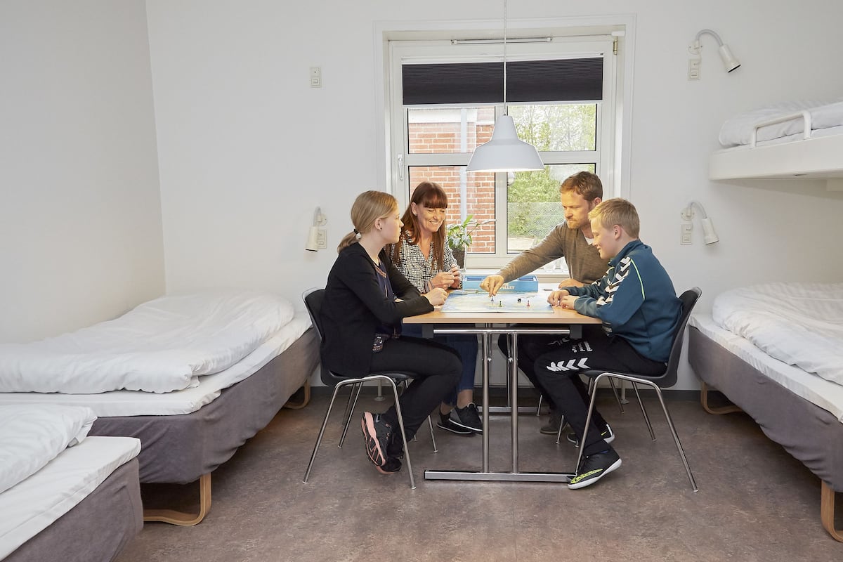A dormitory room with bunk beds, a table, and a window.