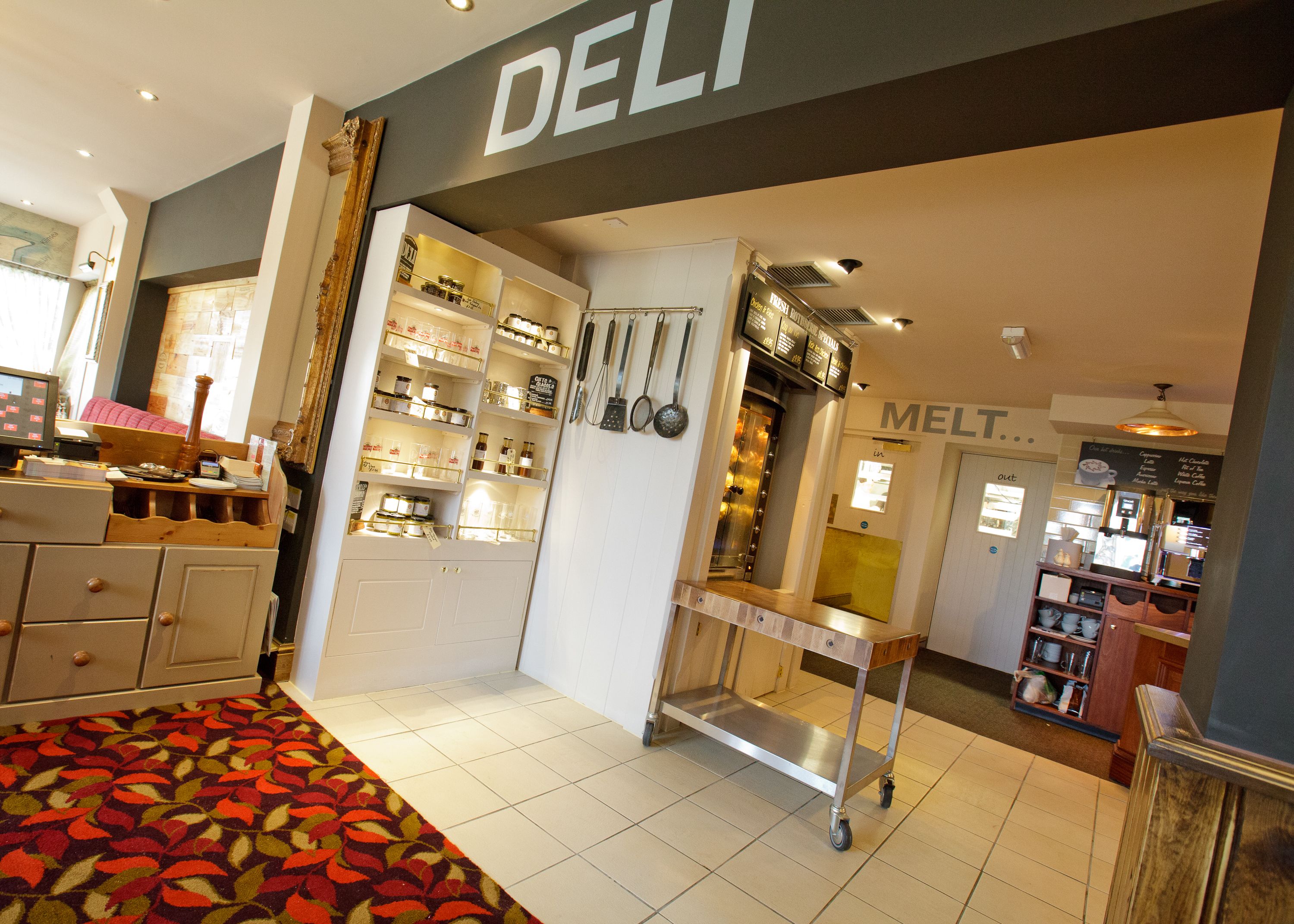 A modern interior with a deli counter, kitchen area, and a patterned carpet.