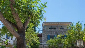 A stone staircase leading up to a building with a stone facade and blue shutters. - Akritas (Pylos-Nestoras)
