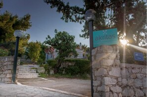A stone wall with a sign reading "akritas" and a lamp post. - Akritas (Pylos-Nestoras)
