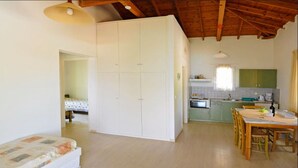 A spacious living area with a wooden ceiling, a dining table, and a kitchen in the background. - Akritas (Pylos-Nestoras)