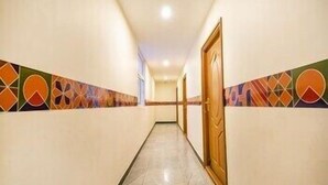 A hallway with patterned walls, a wooden door, and a tiled floor. - FabHotel Thejas Paaradise (Coimbatore)
