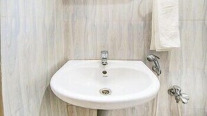 A bathroom with a white sink, a towel hanging on the wall, and a mirror. - FabHotel Thejas Paaradise (Coimbatore)