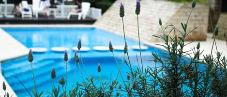 A swimming pool surrounded by lounge chairs and a stone wall.
