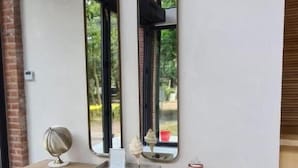 Un banco de madera con un espejo y objetos decorativos frente a una pared lisa.