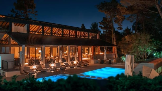 Un edificio moderno con piscina, zona de estar al aire libre y un patio cubierto.