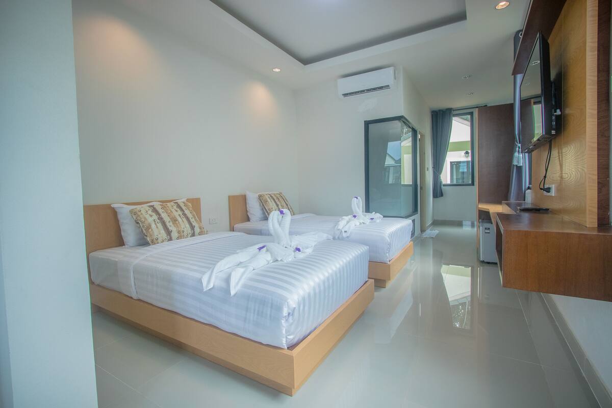 A modern hotel room with two beds, a wooden headboard, a flat-screen TV, and a large window.