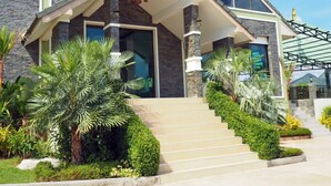 A modern house with a stone facade, a covered porch, and a staircase leading to the entrance. - Saichol Grandview (Ban Ta Khun)