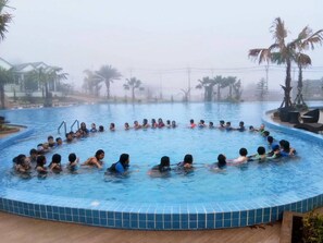 A swimming pool with people in the water, surrounded by palm trees and a cloudy sky. - Saichol Grandview (Ban Ta Khun)