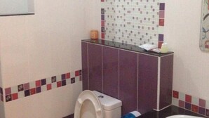 A bathroom with a toilet, sink, and decorative tiles. - Saichol Resort (Chumphon)