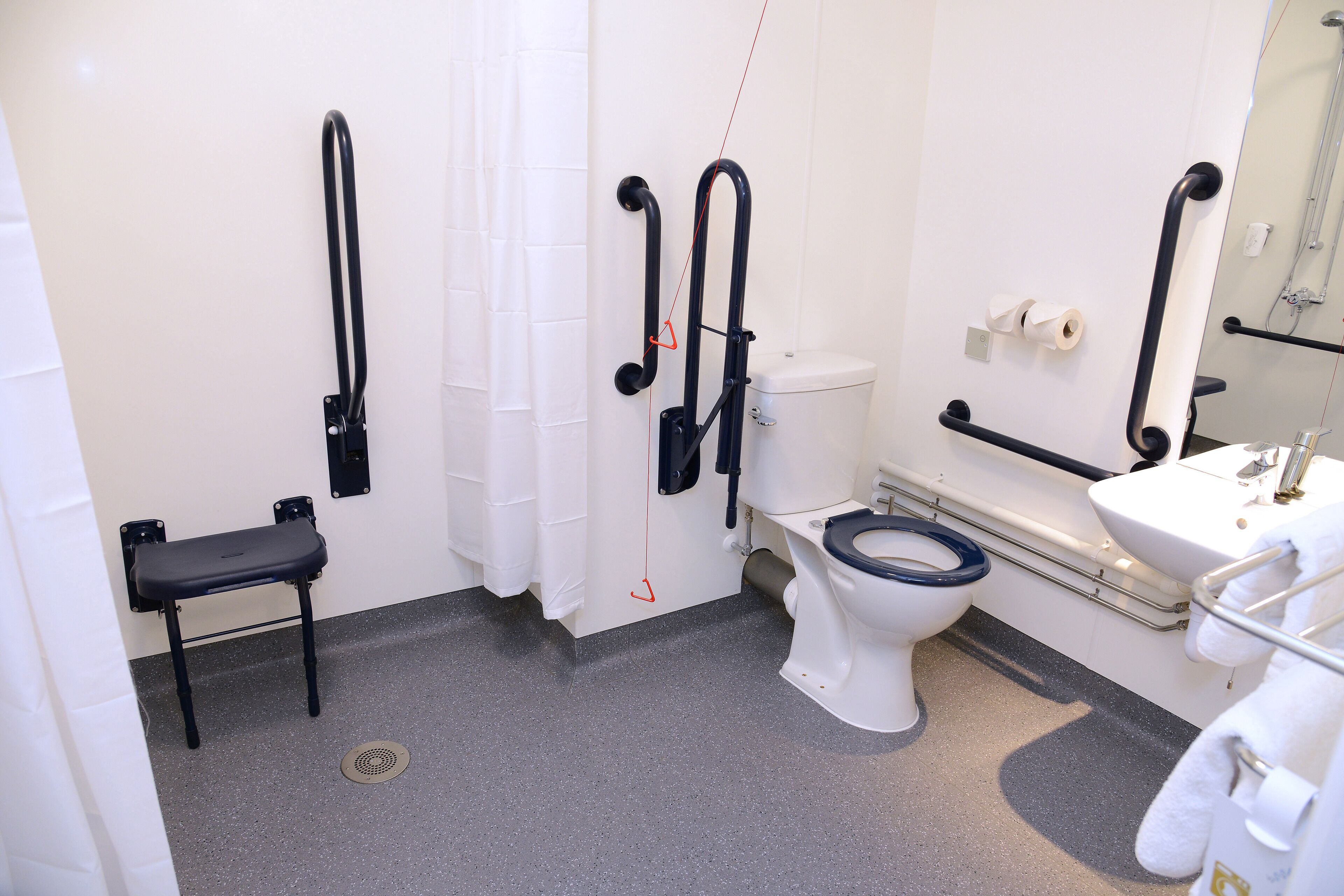 A bathroom with a toilet, bidet, and a bench.