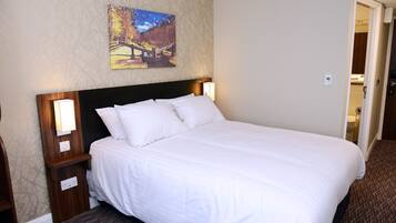 Una cama bien hecha con sábanas blancas, un cabecero de madera y dos lámparas de noche.
