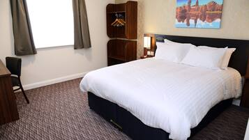 Una camera d'albergo con un letto grande, un armadio in legno, una scrivania e una sedia.