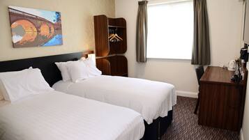 A hotel room with two beds, a wooden wardrobe, a coat rack, and a painting on the wall.