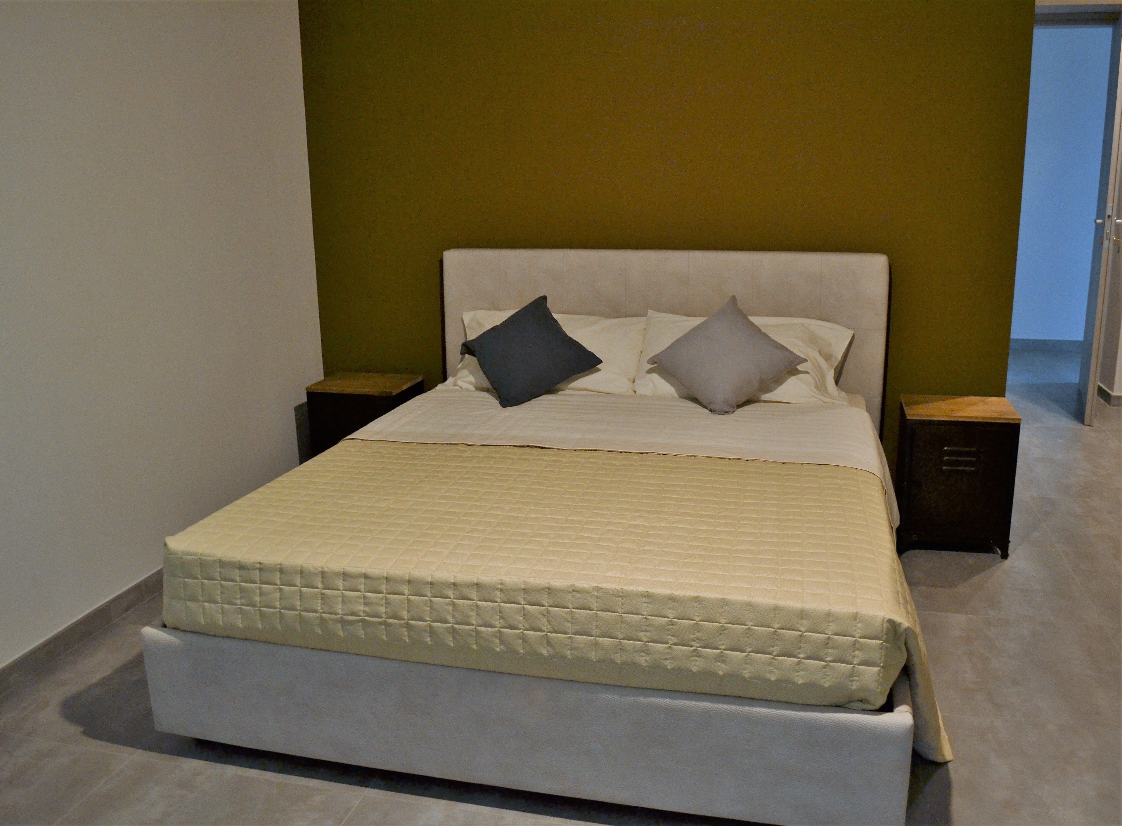 A neatly made bed with a quilted mattress, two bedside tables, and a headboard.