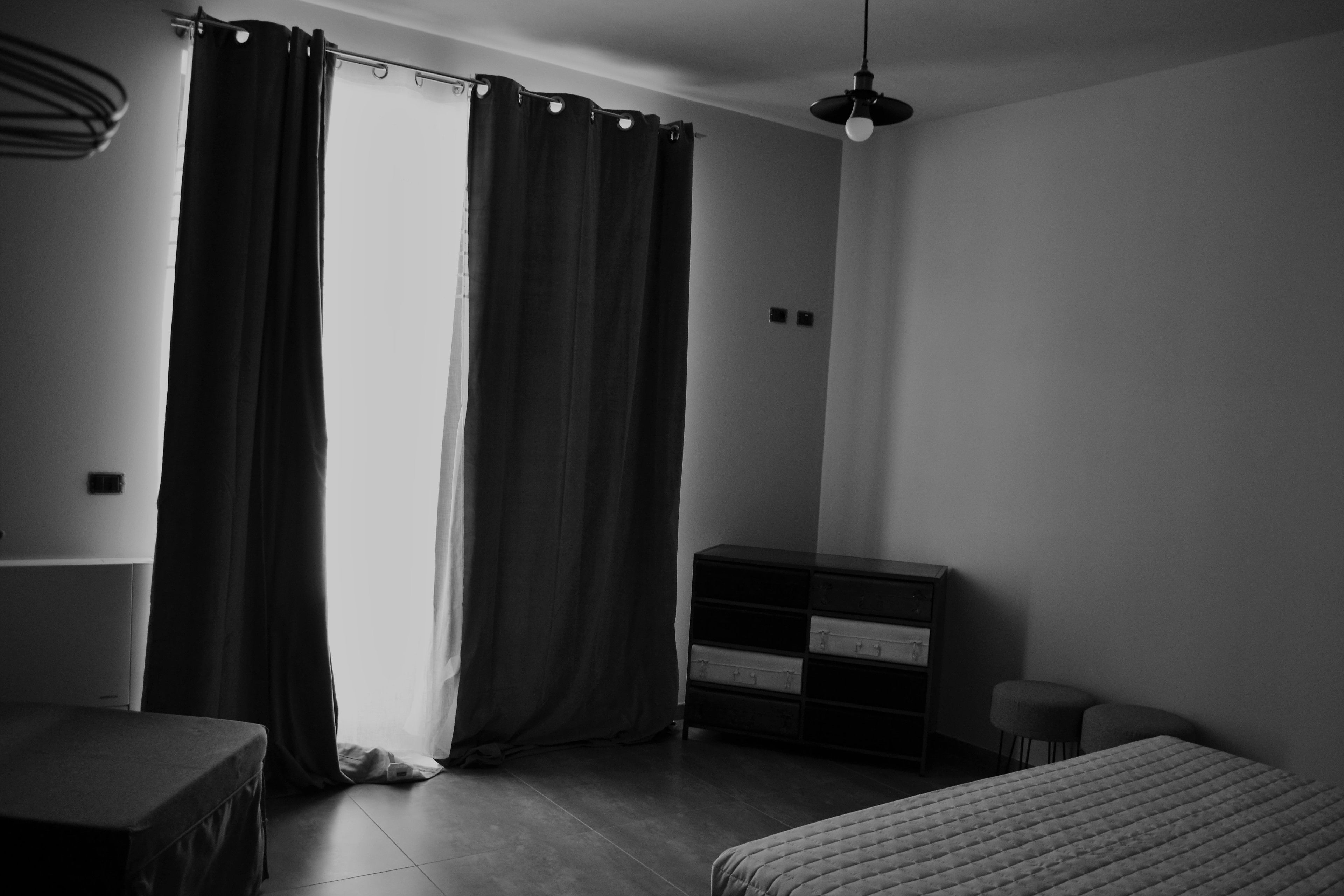 A minimalist bedroom with a bed, a dresser, and a small stool.