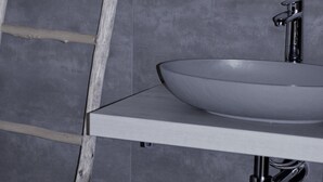 Un baño con un lavamanos blanco, un grifo cromado y una escalera de madera.