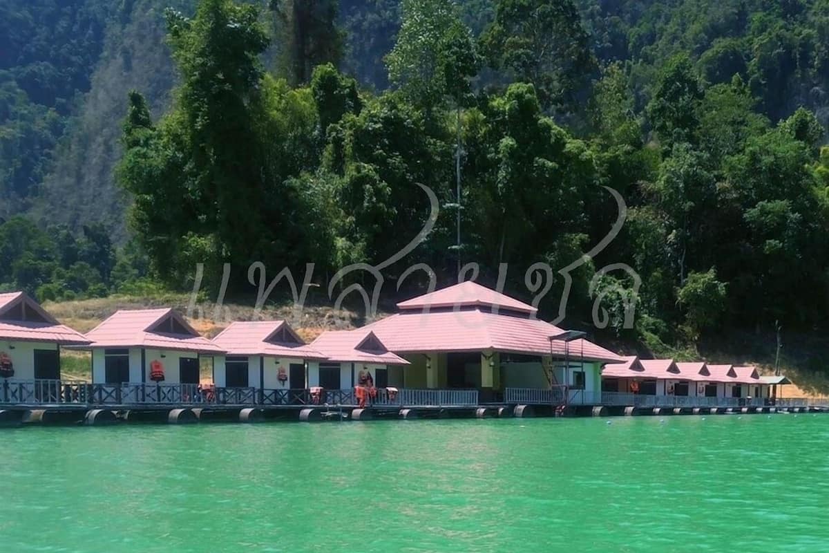 A row of overwater bungalows with a view of the water and forested hills in the background.