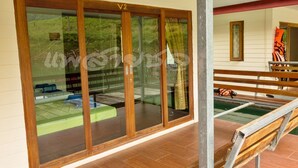 A room with a large sliding glass door leading to an outdoor area with a wooden deck and a bench. - Saichol Floating Resort (Ban Ta Khun)