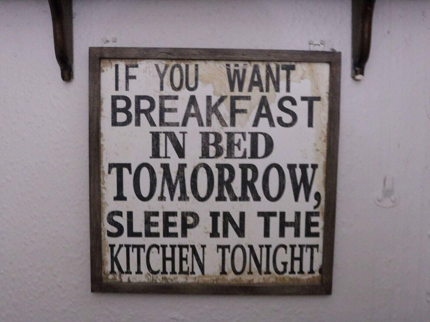 A sign with a humorous message about breakfast and sleeping arrangements.