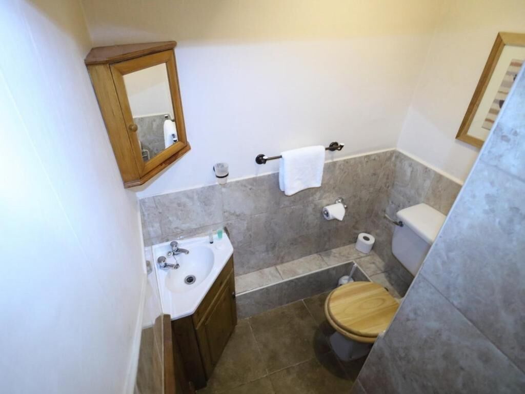 Une salle de bain avec des toilettes en bois, un lavabo, un miroir et un porte-serviettes.