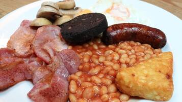 A plate of breakfast food including bacon, sausages, eggs, mushrooms, beans, and toast.