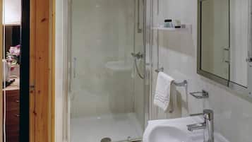 Un baño moderno con cabina de ducha de vidrio, un lavamanos blanco y un espejo sobre él.
