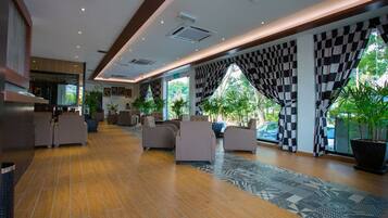 A spacious lobby with a checkered curtain, comfortable seating, and potted plants.