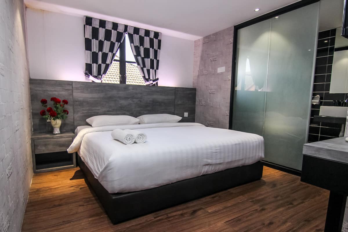 A modern bedroom with a large bed, a nightstand with a vase of red flowers, and a checkered curtain.