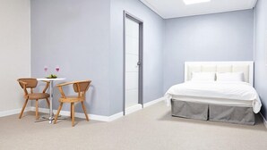 A bedroom with a bed, a door, and a small table with two chairs. - K-Pop Hotel (Gapyeong)