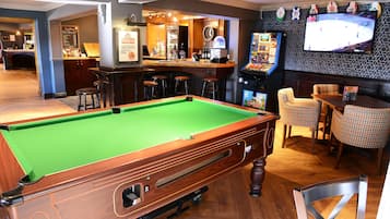 A pool table, bar area, and seating with a television.