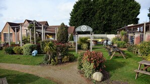 A garden area with picnic tables, a pathway, and a sign for 'Pizzeria Grill'. - Woodcocks, Lincoln by Marston's Inns (Lincoln)
