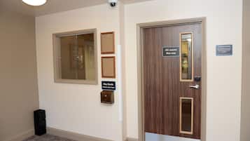 Habitación de hotel con puerta de madera, estación de devolución de tarjetas llave y cámara de seguridad.